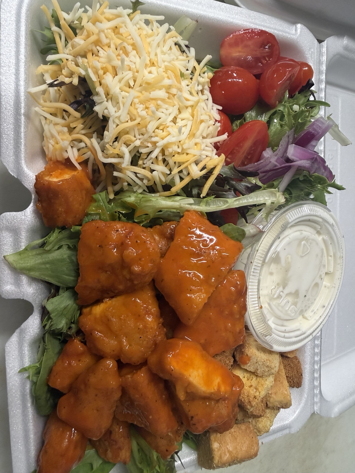 Buffalo chicken salad with greens, tomato, cheese, and dressing